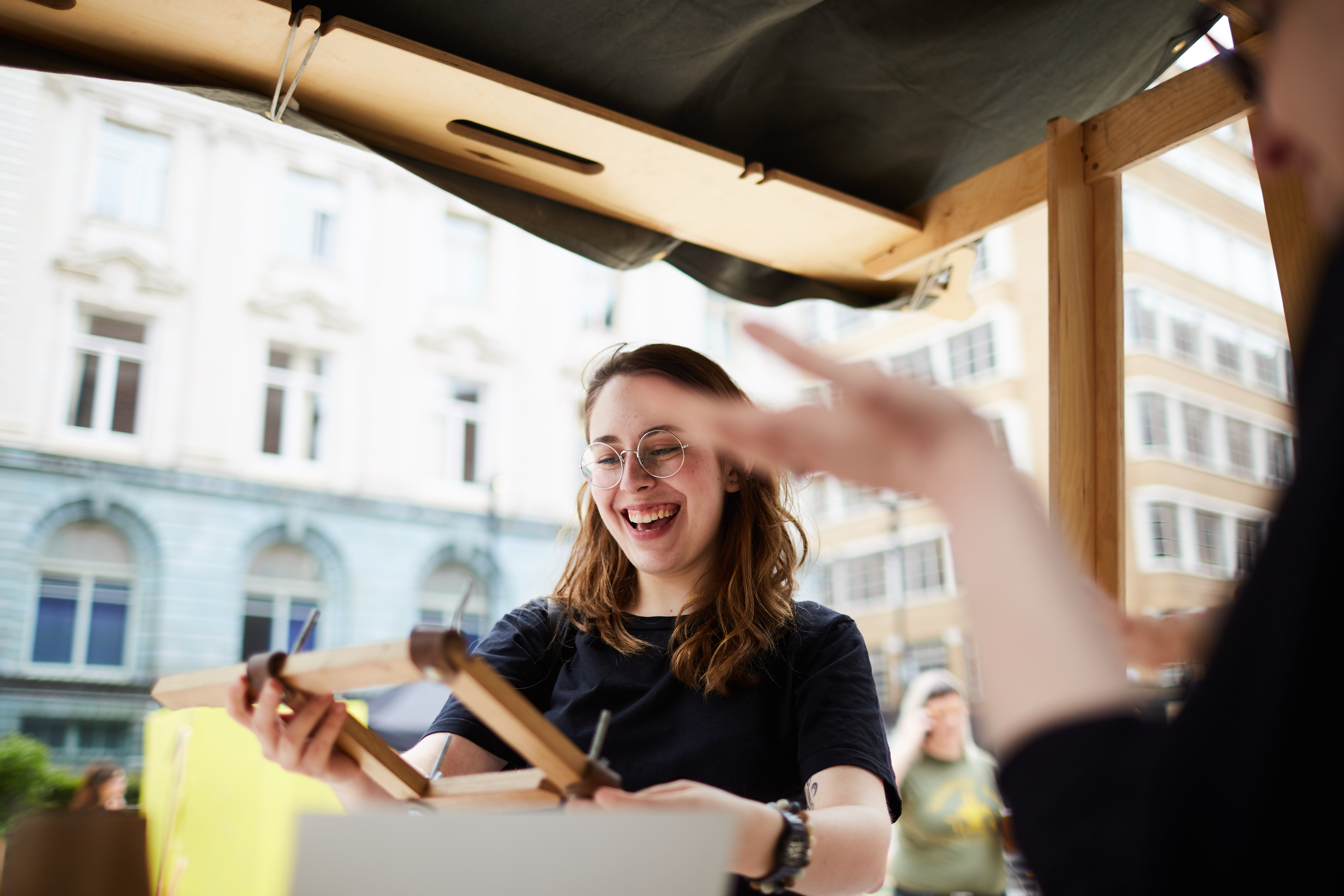 A woman stands smiling at an outdoor market counter.