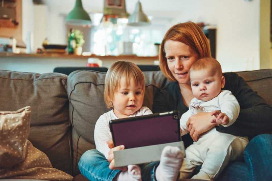 A mother on a sofa with two children and a tablet