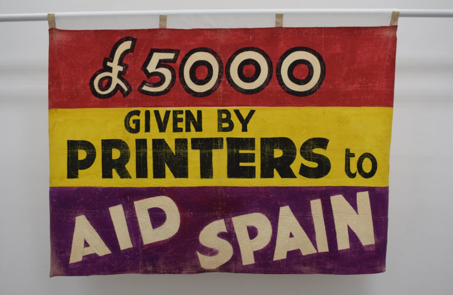 A banner which says "£5000 given by printers to aid Spain".