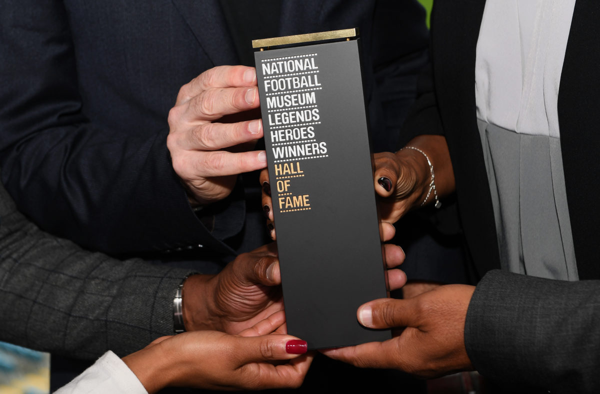 A few pairs of hands hold the a National Football Museum trophy for 'Legends, Heroes and Winners Hall of Fame'.