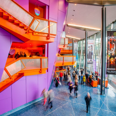 People walking around inside The Lowry in the daytime.
