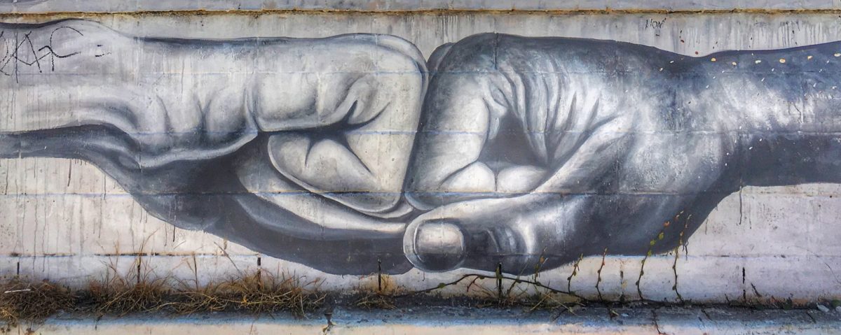 Two fists bump in an original piece of Manchester street art.
