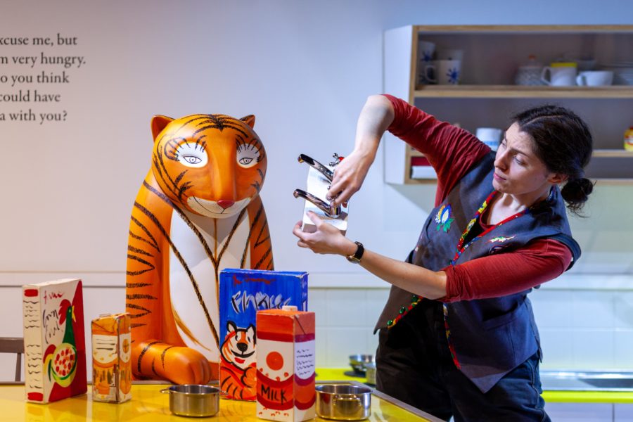 A performer acts out the story from The Tiger Who Came to Tea with a model of the tiger and various props.