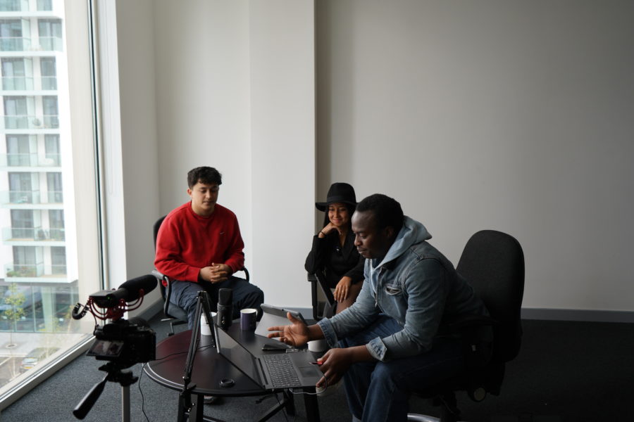 Three young people sit around a laptop for a discussion at the Black Youth Forum.