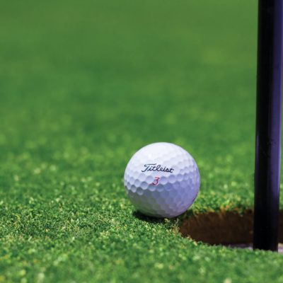 A golf ball sits on a golfing green.