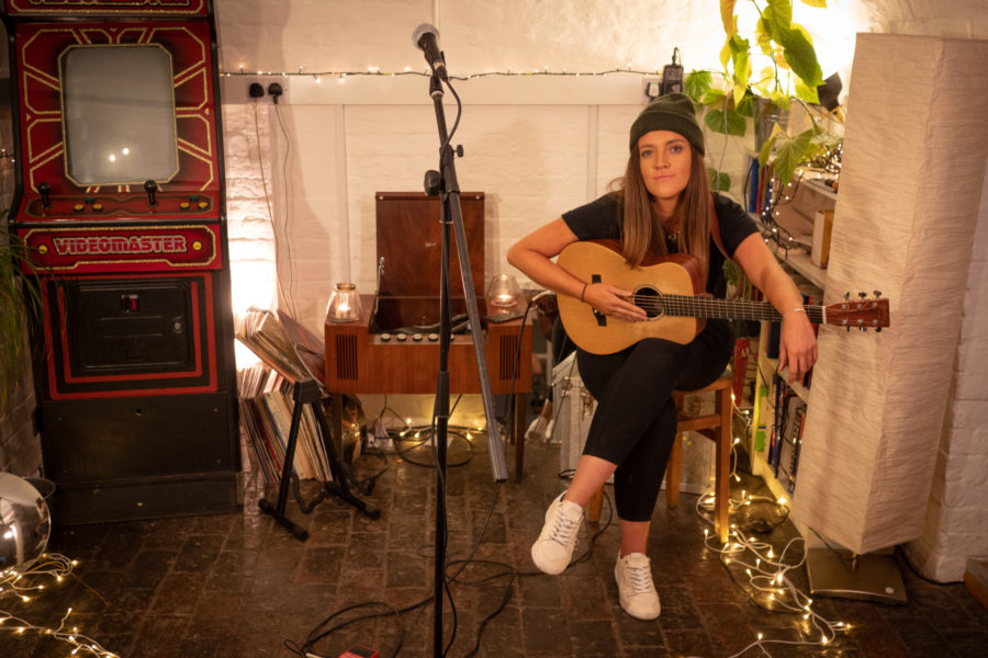 Performer and musician Lauryn Redding sits with a guitar close to her microphone.