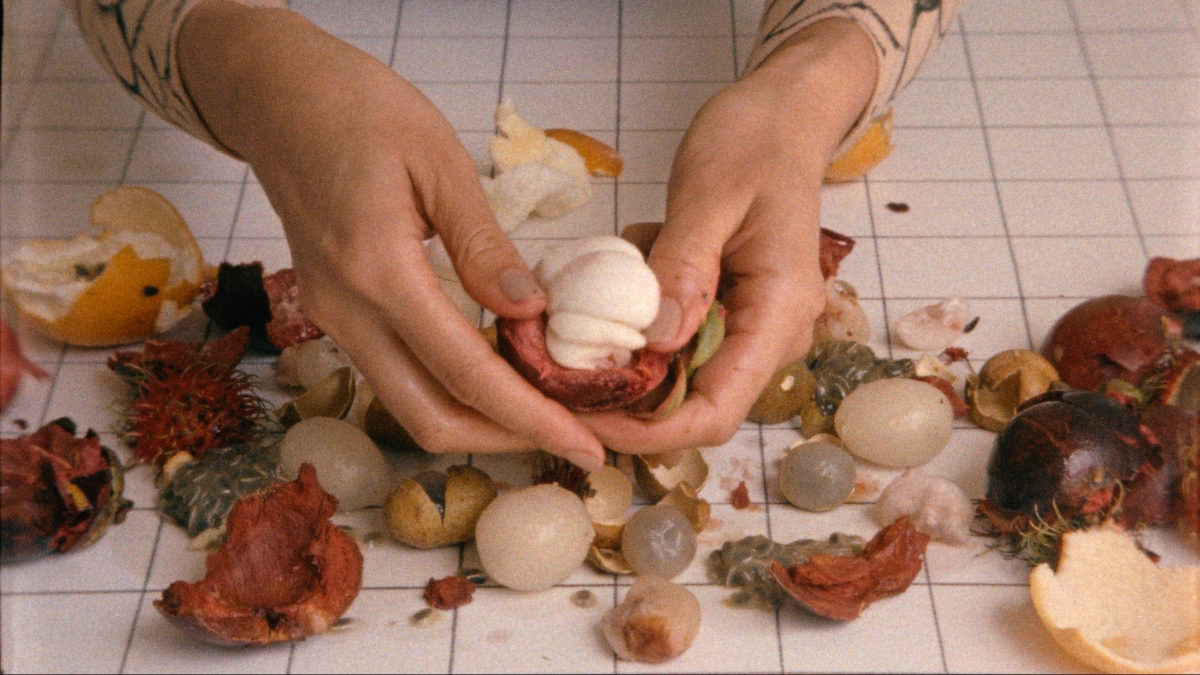A pair of hands pull apart small items of fruit and vegetables in Sriwhana Spong's short film Castle-Crystal.