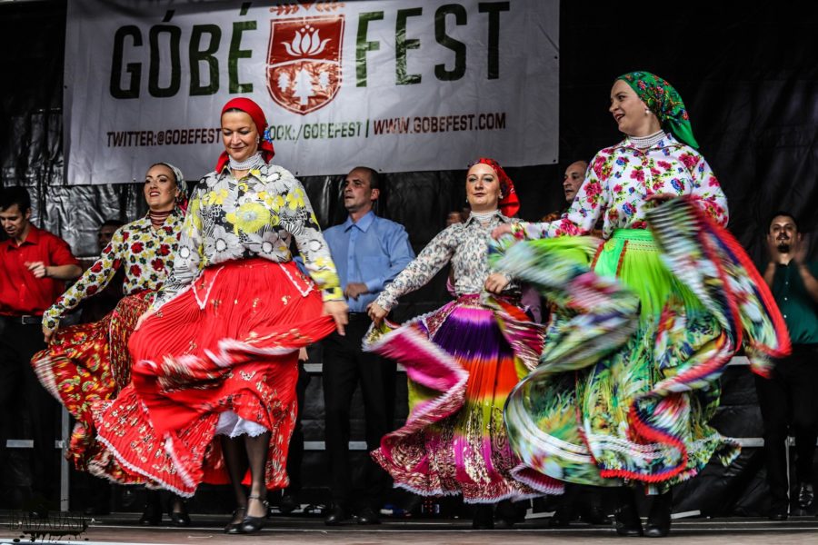 The dancers at Góbéfest wearing bright colourful clothing as they move on stage.