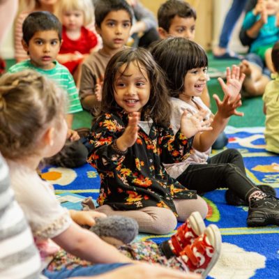 A group of small children sit on the carpet at their local library.