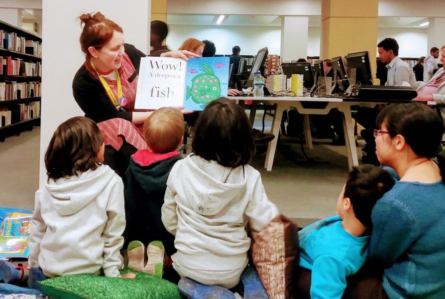 Children sat on the florr being read to and shown a book