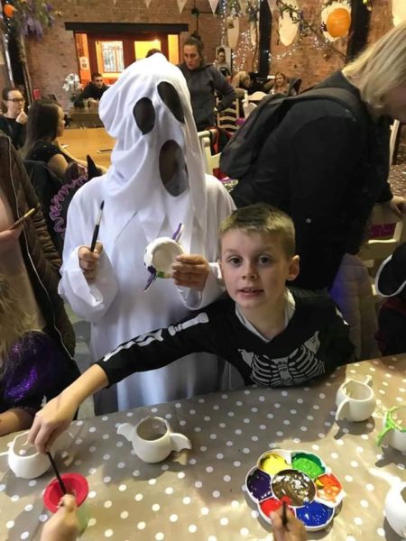 Two children in Halloween fancy dress enjoy pot painting at Wythenshawe Park.