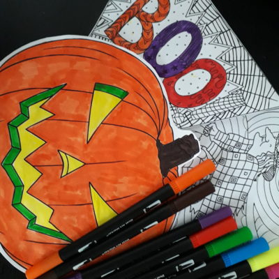 A brightly coloured picture of a pumpkin, a colouring in activity sheet and some felt tip pens.