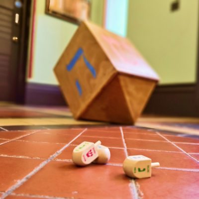 A game of driedel takes place on a tiled floor.