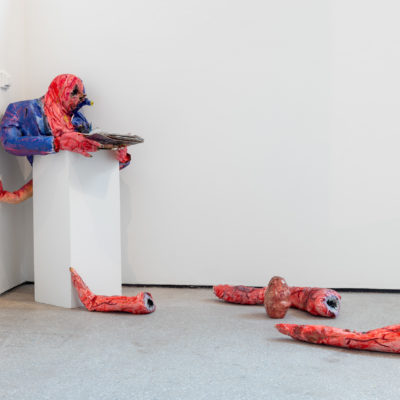 An art sculpture is in pieces on the floor of an art gallery.
