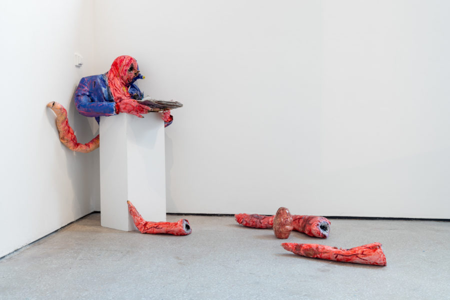 An art sculpture is in pieces on the floor of an art gallery.