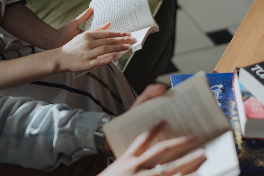 Two sets of hands each holding a book