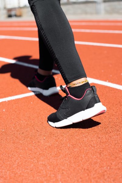 A person wearing black trainers in an athletics stadium