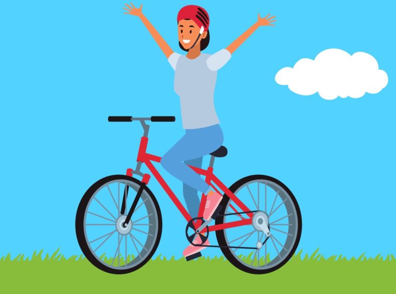 A person cycling a bike raises their hands up in the air