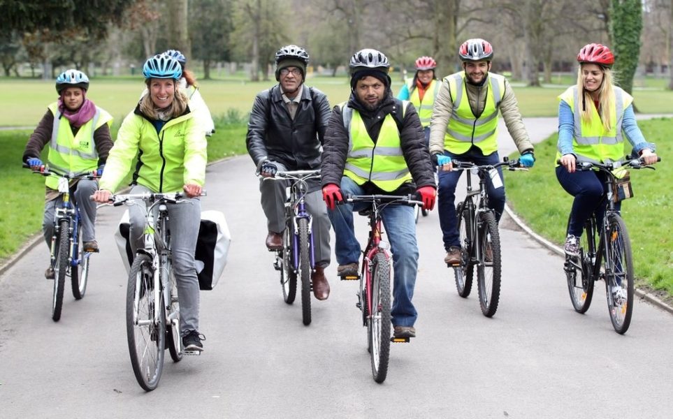 A group of seven people wearing hi-vis vests riding their bikes down a pathway