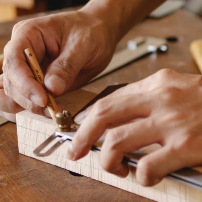 A pair of hands working on a piece of wood.