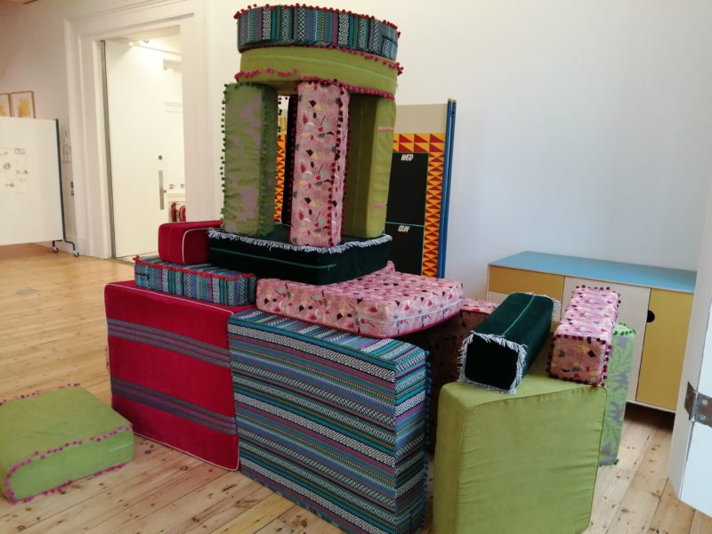 A multi-coloured den made out of different sized cushions.