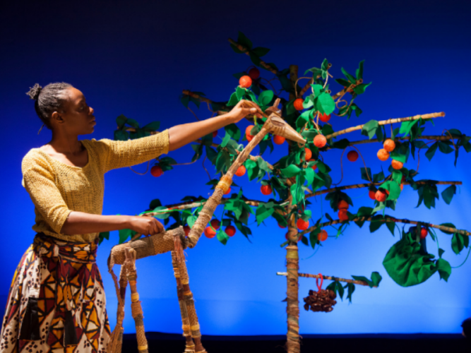 Handa is operating a puppet who is eating fruit from a tree