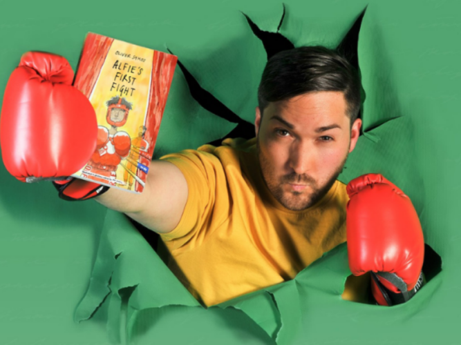 Alfie is bursting out of a green background wearing boxing gloves and holding his diary. He is wearing a yellow t shirt.