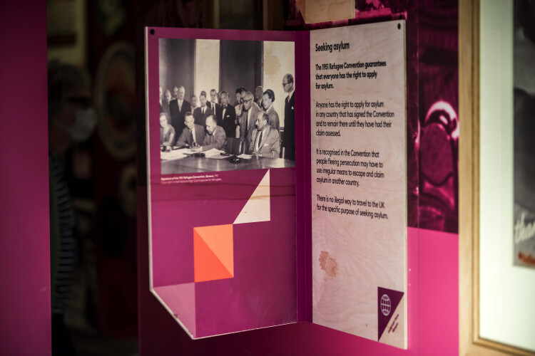 Pink and white information board with black & white photograph of the meeting for the 1951 Human Rights convention