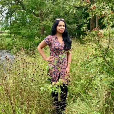 Author Anita Sethi stands in a woodland area