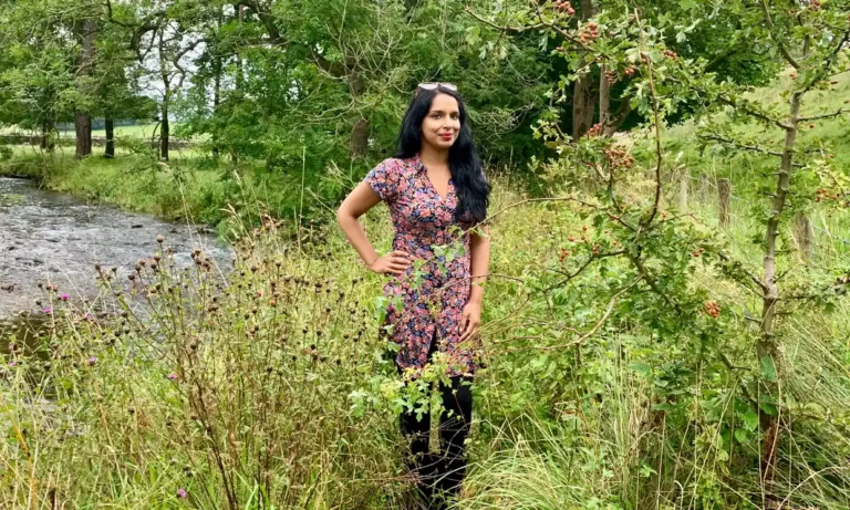 Author Anita Sethi stands in a woodland area