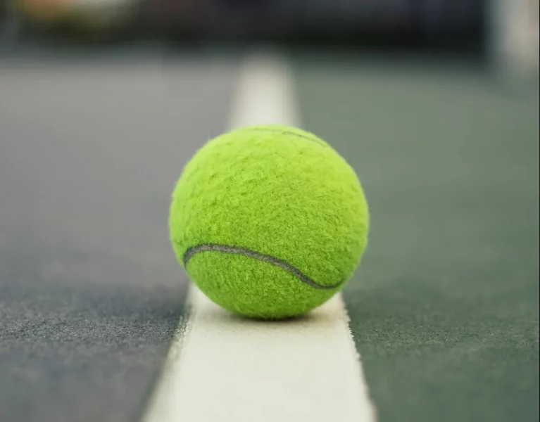 A tennis ball sits on a white line