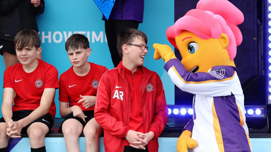 Three young footballers with the Women's Euro 2022 mascot Ashley.